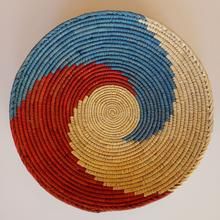 a colorful woven basket is displayed on a white surface with an orange, blue, and red design