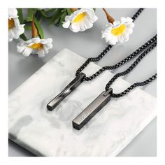 two long necklaces on a marble slab with flowers in the backgroung