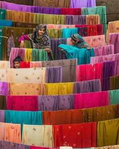 two women standing in front of colorful cloths