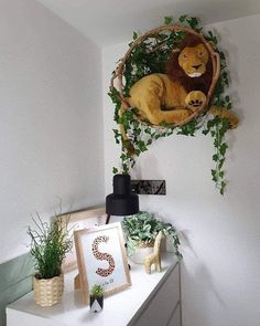 there is a stuffed lion in the basket on the wall next to some potted plants