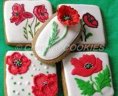 decorated cookies with red flowers and green leaves on a green tableclothed surface,