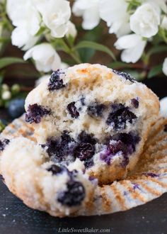 two blueberry muffins sitting on top of a plate next to white flowers