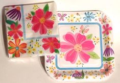 two square plates with flowers on them are sitting next to each other in front of a white background