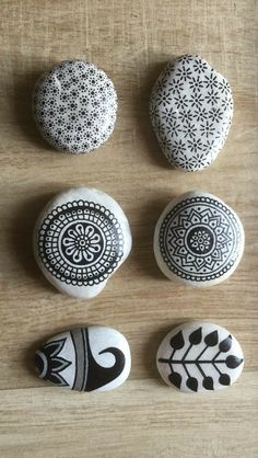 four black and white rocks sitting on top of a wooden table