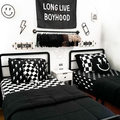 two beds with black and white checkered sheets in a room decorated with wall hangings