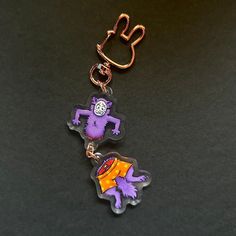 two key chains with cartoon characters on them sitting next to each other in front of a black surface