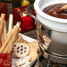 a bowl of chocolate and crackers on a table with other snacks in front of it