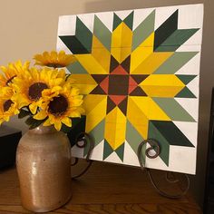 two sunflowers are in a vase next to a painting on a wooden table