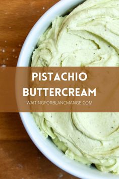 a white bowl filled with green cream on top of a wooden table and text overlay reads, pistachio buttercream