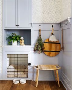 a kitchen with white cabinets and wood floors, including a dog crate on the floor