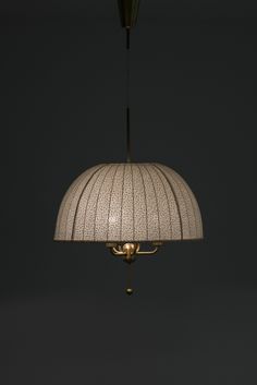 a white lamp hanging from the ceiling in a dark room with a black wall behind it