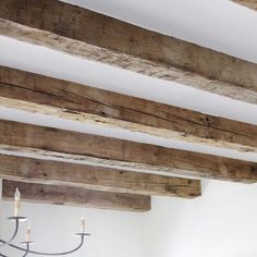 a chandelier hanging from the ceiling in a room with wood beams and white walls