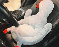 a stuffed animal sitting in the driver's seat of a car with steering wheel