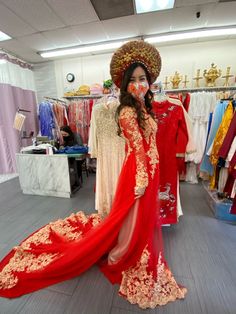 a woman in a red and gold dress standing next to a mannequin wearing a headdress