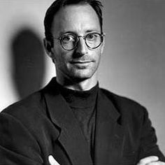 black and white photo of a man wearing glasses with his arms crossed in front of him