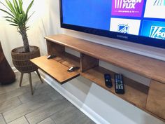 a flat screen tv sitting on top of a wooden shelf next to a potted plant