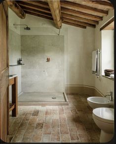 a bathroom with two sinks and a walk in shower next to a toilet under a wooden beam