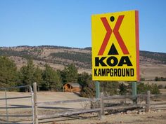 a yellow and red sign sitting on the side of a road next to a forest