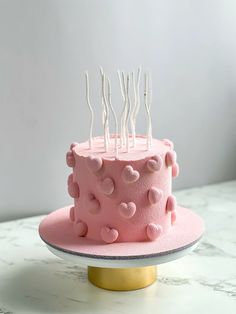 a pink cake with white candles on top