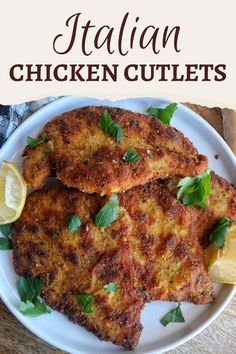 chicken cutlets on a white plate with lemon wedges