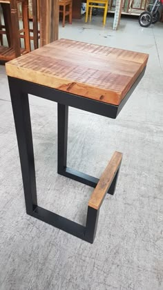 a wooden table with metal legs and a bench on the floor in a room full of chairs