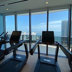 there are treadmills in front of the window overlooking the cityscape and ocean