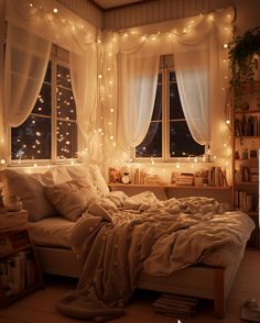 an unmade bed in front of a window with fairy lights