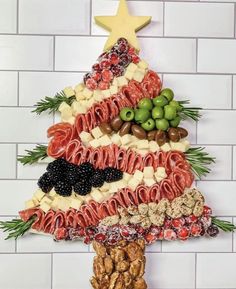 a christmas tree made out of meats, cheeses and olives on a white tiled wall