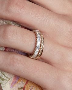 a woman's hand with a gold and white diamond ring on top of it