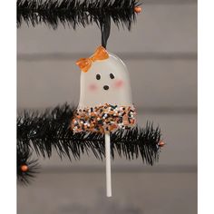 an ornament hanging from a christmas tree decorated with orange and white decorations,