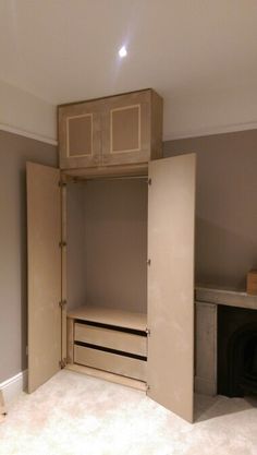 an empty room with a closet and desk in the corner, next to a fire place