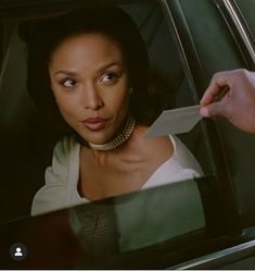 a woman sitting in the back seat of a car holding onto a piece of paper