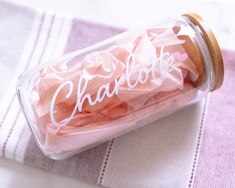 a jar filled with pink tissue paper and the word charlotte written in white on it