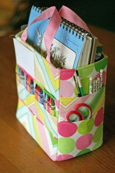 a colorful bag is sitting on a table with scissors and books in it's pocket