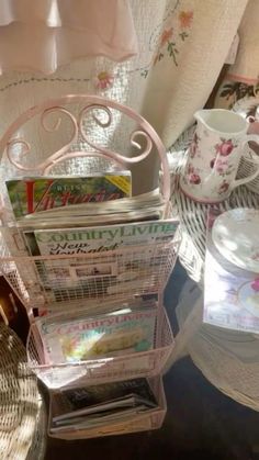 a stack of magazines sitting on top of a table next to a cup and saucer