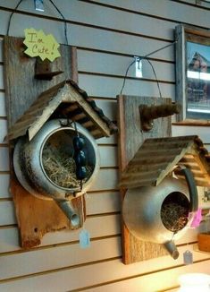 two bird houses hanging on the side of a wall with birds in it's feeders