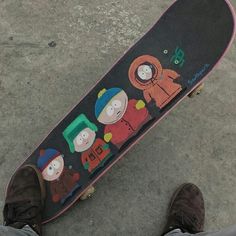 a person standing next to a skateboard with cartoon characters on it's side