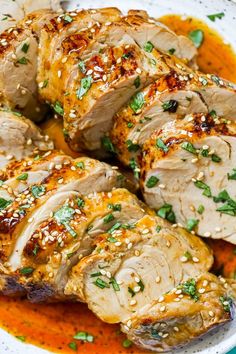 sliced pork with sesame seeds and garnishes in a white bowl