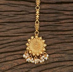 Indian Bridal Traditional One Gram Jewelry Tikka Height = 155 mm || Width = 32 mm Plain Gold Tikka Antique Maang Tikka Gorgeous 24 K gold plated. Whether you are the bride or sassy bridesmaid, no lehenga is complete without a maang tikka. This Kundan pearl maang tikka is perfect to steal the show with its elegance . The meticulous attention paid to the craftsmanship makes it an epitome of jewelry inspiration. 100% Satisfaction Guarantee: Long Lasting Plating, High-Quality Stones. Gifting: This p Festive Temple Jewelry Tikka With Motifs, Intricate Design Tikka For Puja And Diwali, Festival Puja Tikka With Intricate Design, Festive Puja Tikka With Intricate Design, Festivals Puja Tikka With Intricate Design, Temple Jewelry Round Tikka With Cutdana, Temple Jewelry Round Cutdana Tikka, Temple Jewelry Tikka For Puja With Intricate Design, Heavy Temple Jewelry Tikka For Navratri