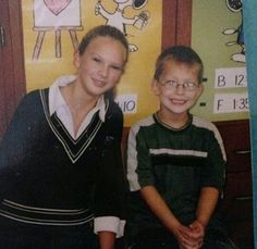 two young boys sitting next to each other in front of a wall with mickey mouse pictures on it