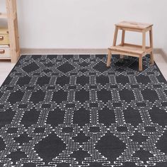 a black and white area rug with geometric design on the floor next to a wooden chair