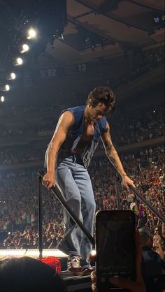 a man standing on top of a metal pole in front of a crowd at a concert