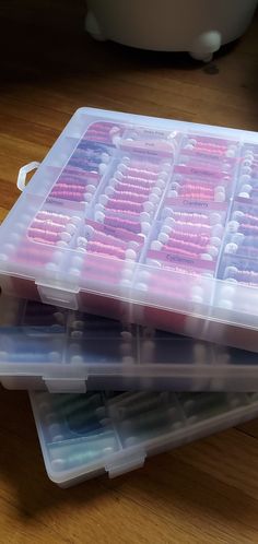 two plastic containers filled with pink and blue toothbrushes on top of a wooden table