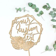 a cake topper with the words your custom text surrounded by greenery and leaves