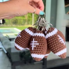 a hand holding two crocheted football key chains