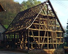 an old wooden building with wood shingles on the roof and side walls is being built