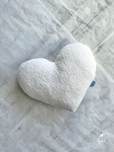 a white heart shaped pillow sitting on top of a table