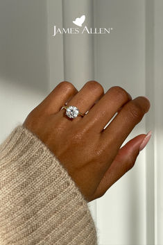 a woman's hand with a diamond ring on her left hand and the words james allen above it