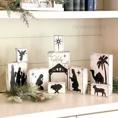 wooden blocks decorated with nativity and silhouettes are sitting on a shelf in front of bookshelves