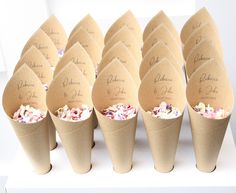 a bunch of paper cones that are sitting on a white tablecloth with flowers in them